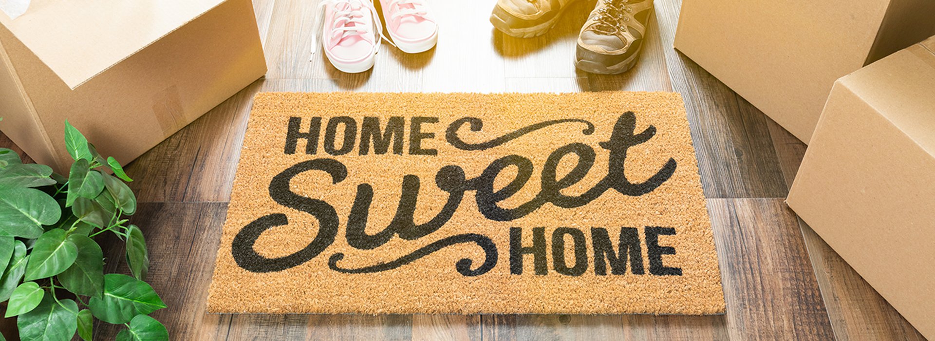 Home Sweet Home Welcome Mat, Moving Boxes, Women and Male Shoes and Plant on Hard Wood Floors.